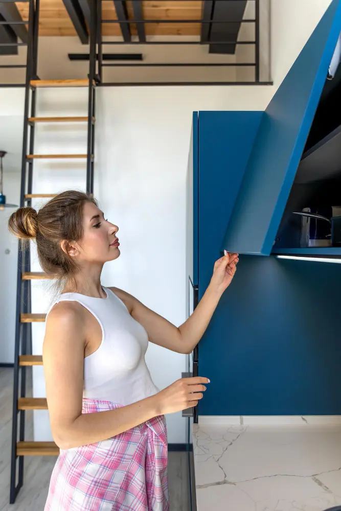 Homeowner viewing a modern blue kitchen cabinet with lift-up door